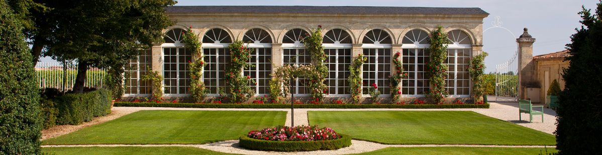 Gebäude und Garten auf Château Branaire-Ducru mit einer großen Fensterfront und teilweise begrünter Hauswand