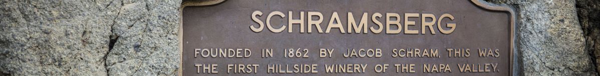 Plakette mit Text zur Geschichte von Schramsberg an einer Steinmauer