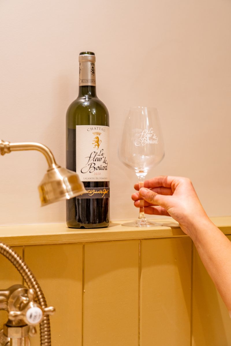 Weinflasche und Weinglas stehen auf einer Ablage von Chateau La Fleur de Bouard