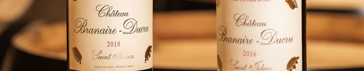 Zwei Rotweinjahrgänge von Château Branaire-Ducru vor Holzweinfässern