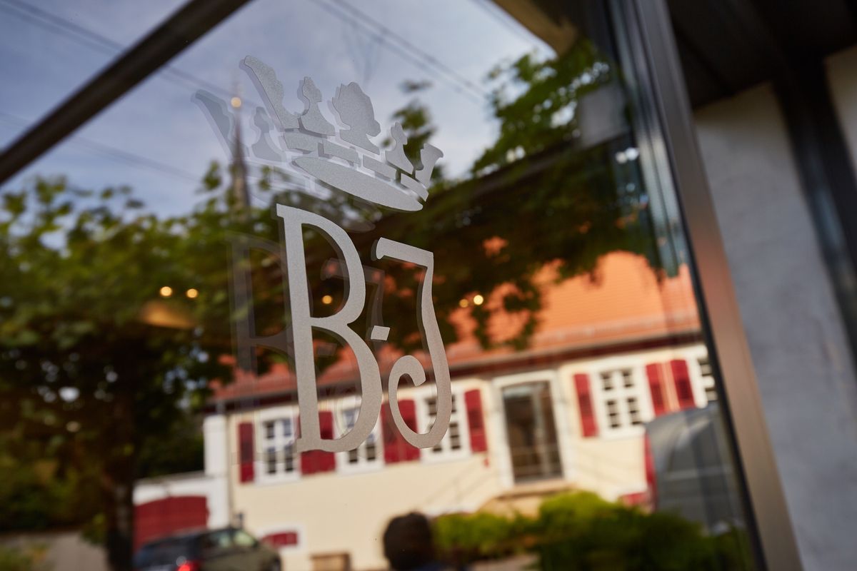 Bassermann Jordan Logo and Fenster mit Weingutsgebäude im Hintergrund