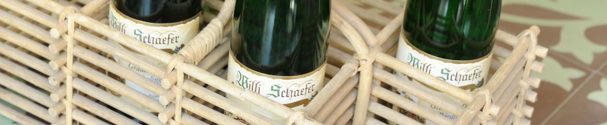 Drei Weinflaschen des Weinguts Willi Schaefer in einer Tragetasche aus Bast.