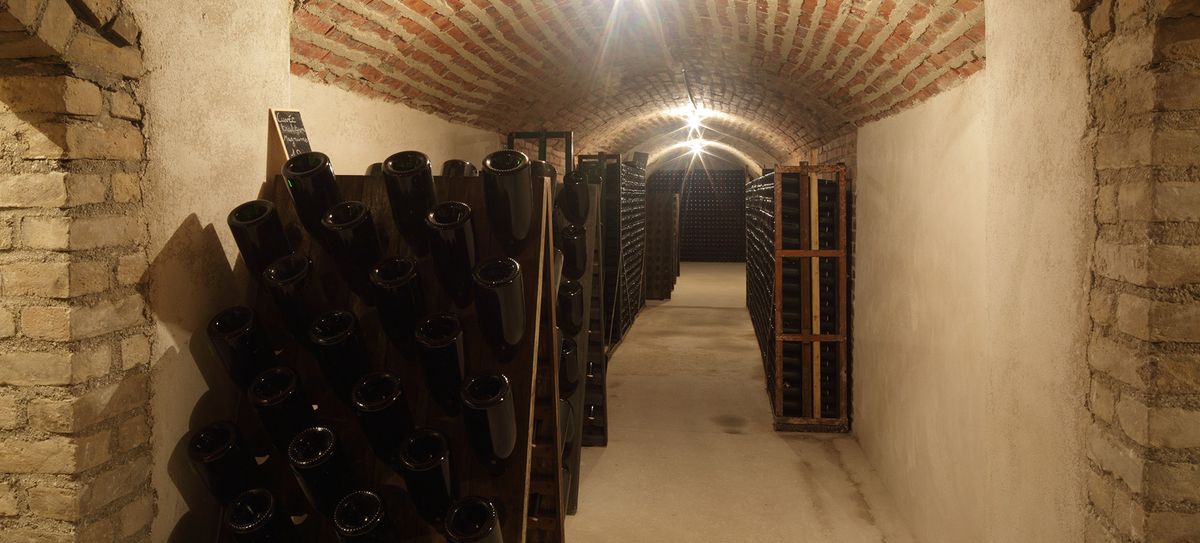 Langer Gang von Steinweinkeller mit Weinflaschenregalen von Chateau Coutier