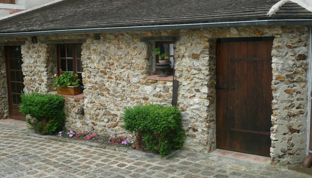 Kleines Haus in Steinoptik mit zwei Holztüren und zwei Buchsen