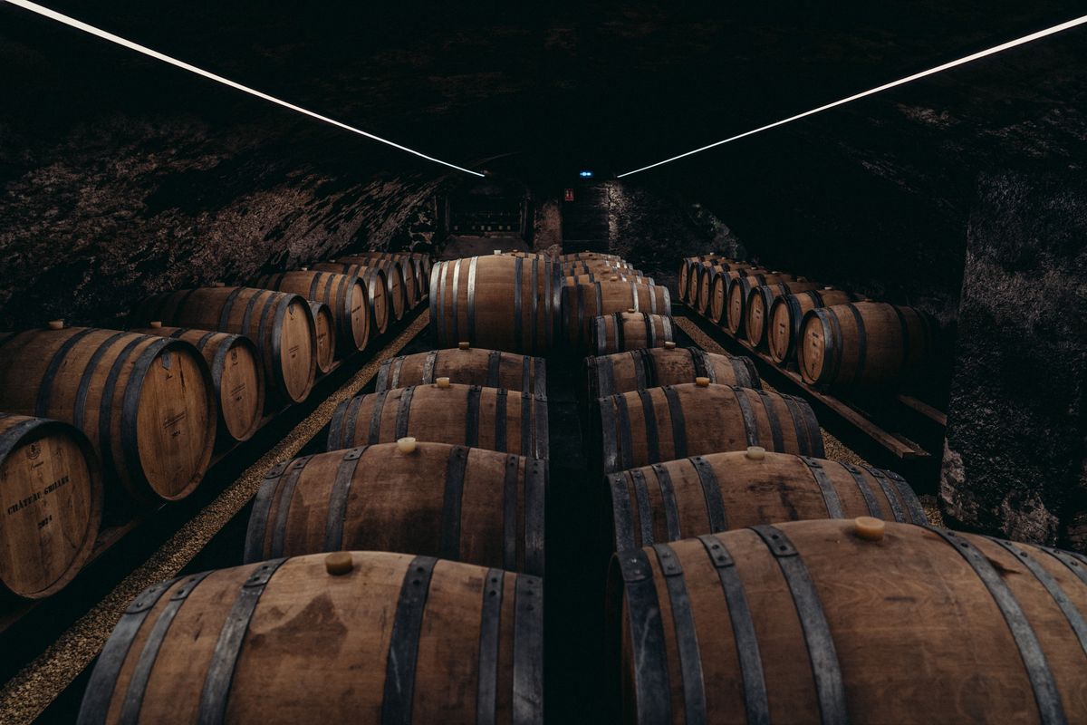 Weinkeller mit liegenden Holzweinfässern in dunklem Steinkeller von Chateau Grillet
