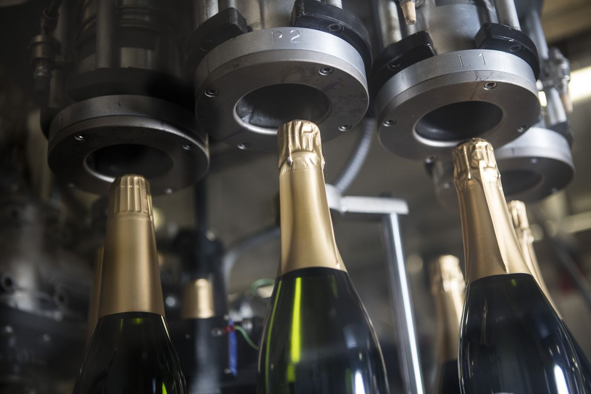Champagnerflaschen die mit Hilfe einer Maschine verschlossen werden