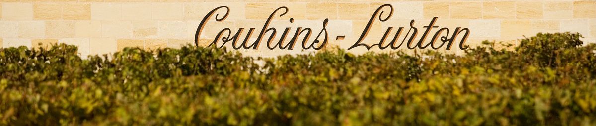 Schriftzug Château Couhins-Lurton an einer Hauswand, davor Weinreben.