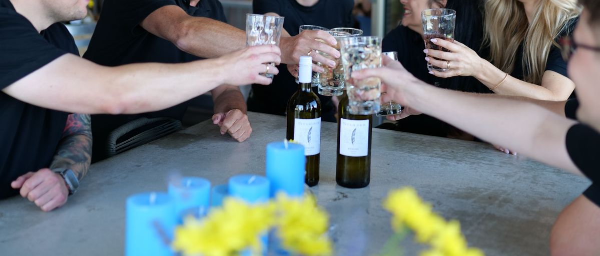 Hände Stoßen mit Gläsern zusammen mit Weinflaschen von Weingut Studier in der Mitte