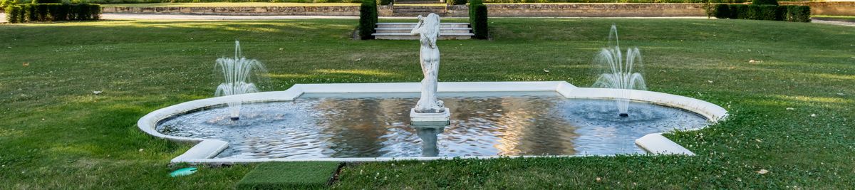 Springbrunnen mit Frau in der Mitte auf einer Wiese