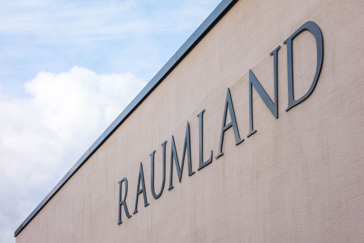 Hohe Beige Wand mit dem Schriftzug "Raumland" darauf