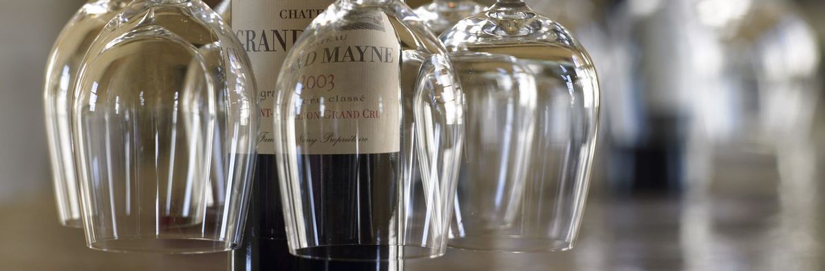 Weinflasche von Chateau Grand Mayne mit Weingläser hängend von der Weinflasche