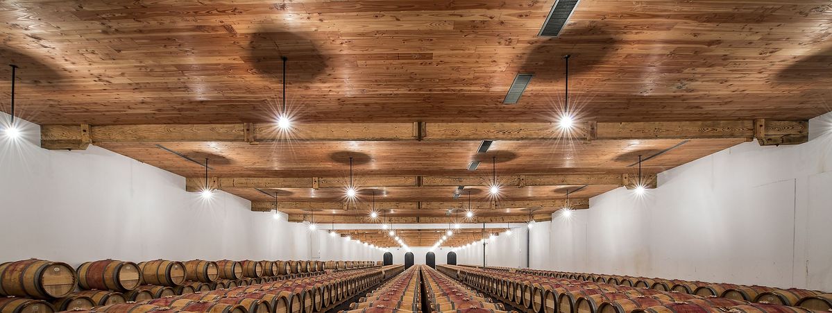 Decke mit Holzbalke und Lichter über Holzweinfässer von Chateau Duhart Milon Rothschild