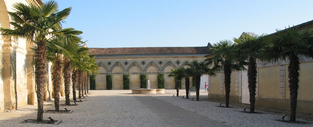 Innenhof von Château Cos d'estournel mit Palmen und Springbrunnen bei Sonnenschein