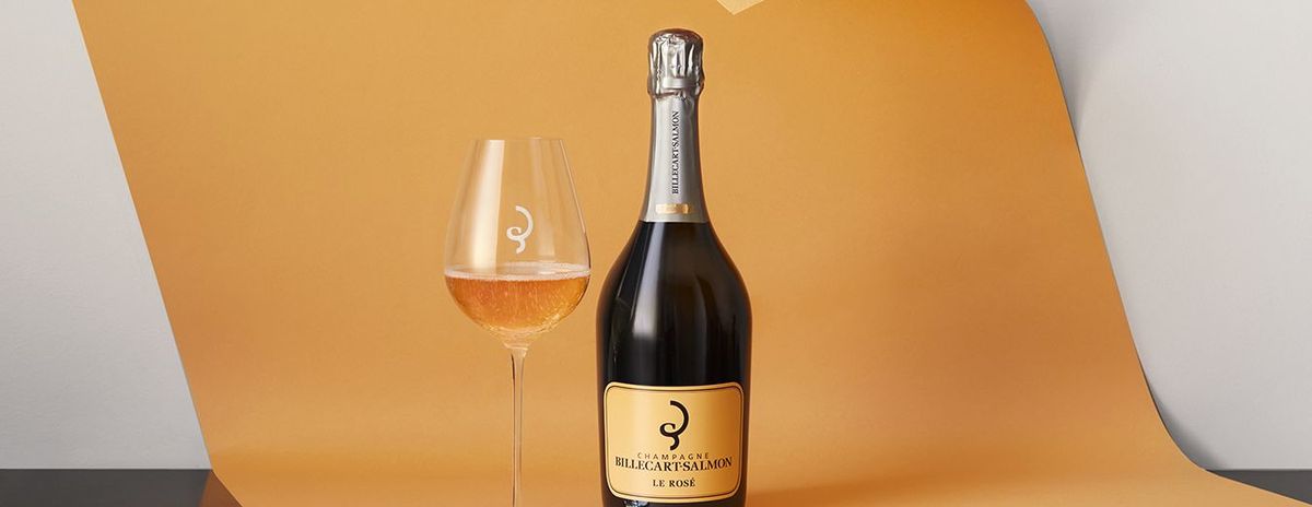 Flasche Wein und ein Weinglas stehend auf Orangem Papier