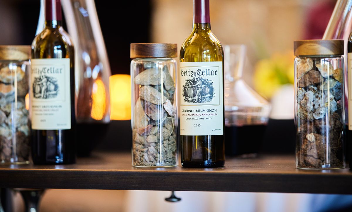 Drei Weinflaschen vom Weingut Heitz sehen jeweils neben einer Säule, die mit Steinen gefüllt ist.