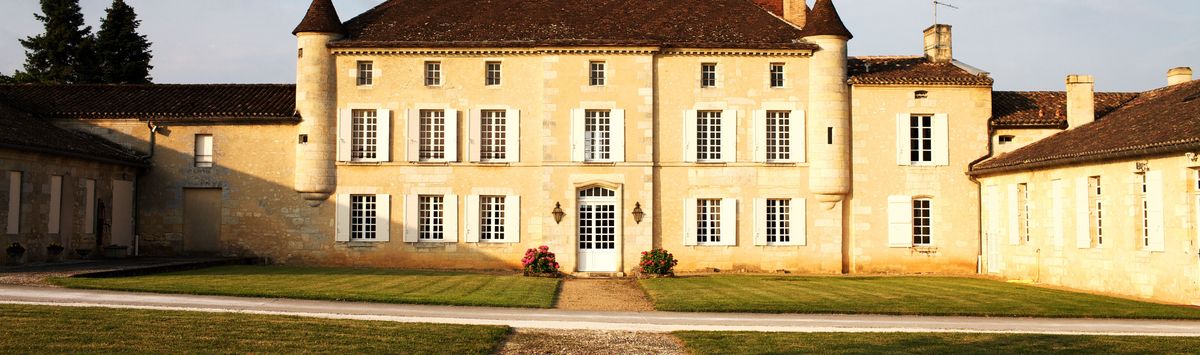 Gelbes Schloss von Chateau Grand Mayne mit grünen Wiesen und Kieselzufahrt