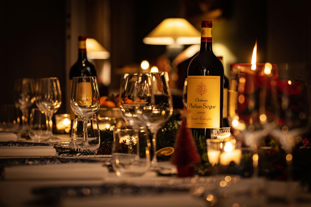 Weihnachtlich gedeckter Tisch mit Kerzen und Weinflasche von Chateau Phelan Segur