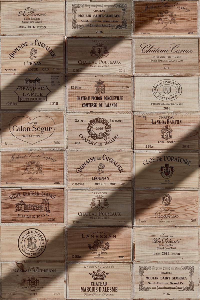 Gestapelte Holzkisten von Bordeaux Grand-Cru-Weinen mit eingebrannten Château-Namen