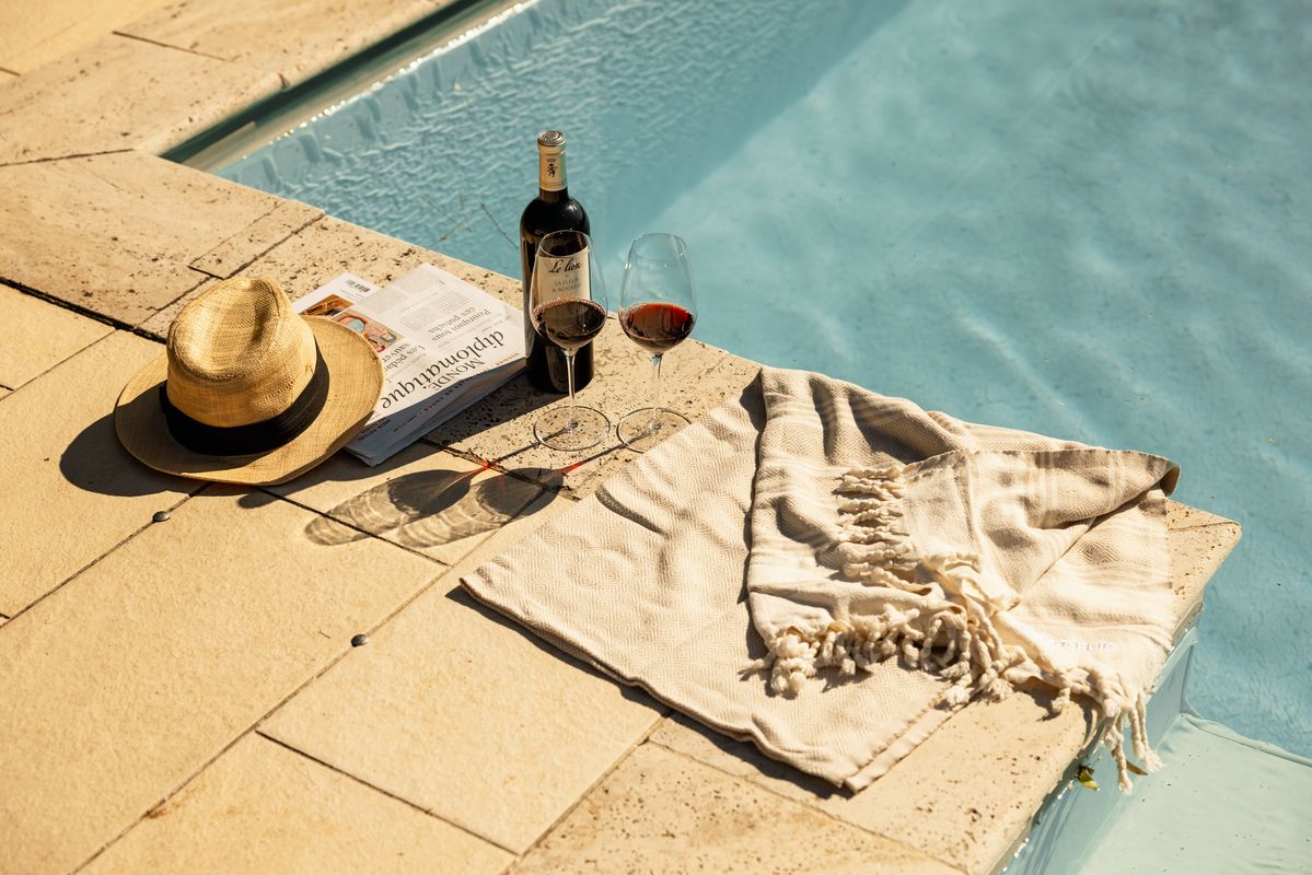 Picknickdecke mit Hut, Sonnenbrille, Weinflasche und zwei Weingläser am Pool von Chateau La Fleur de Bouard