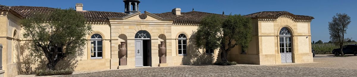Außenansicht vom Innenhof mit Pflastersteinboden auf die Gebäude Weingut Petrus  und bei Tageslicht.