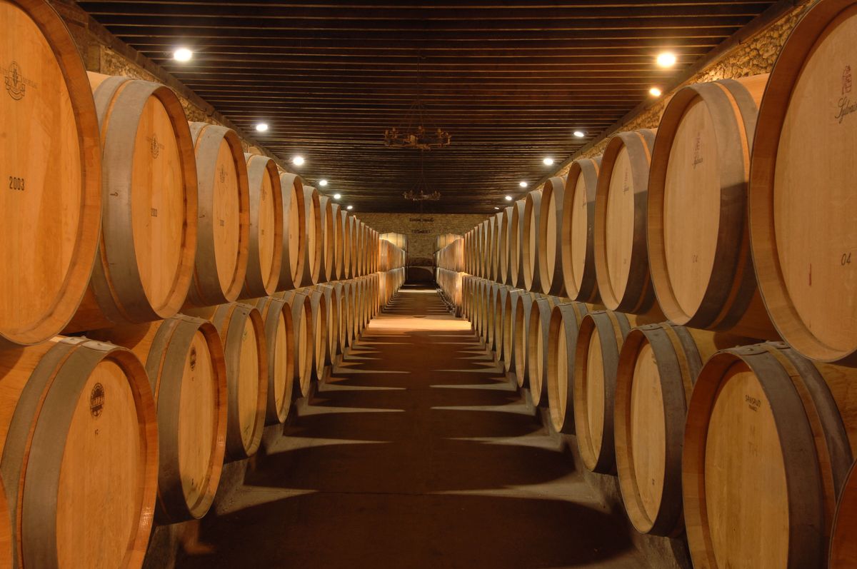 Langer Gang eines Weinlagers mit Holzkisten in Stahlregalen von Chaeteau de Pez