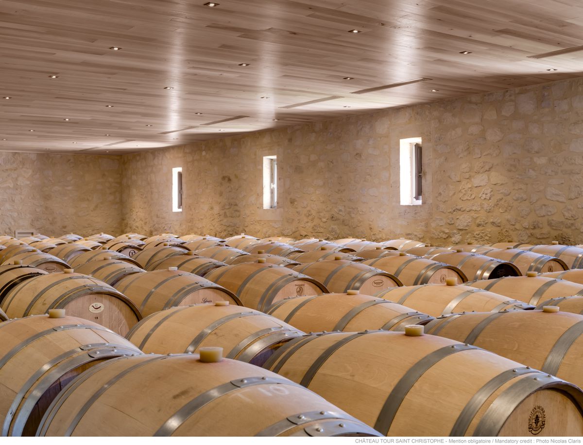 Weinkeller von Chateau Tour Saint Christophe mit aneinandergereihten Holzweinfässern