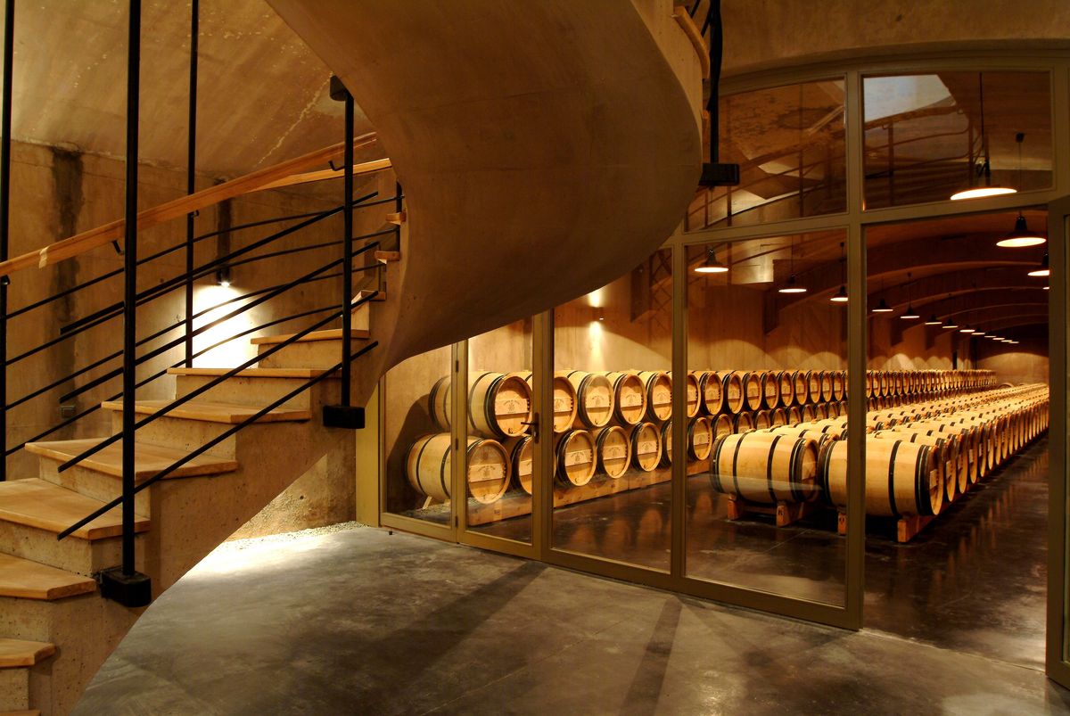 Weinkeller von Chateau Giscours mit Holztreppe und Holzweinfässern hinter Glaswand