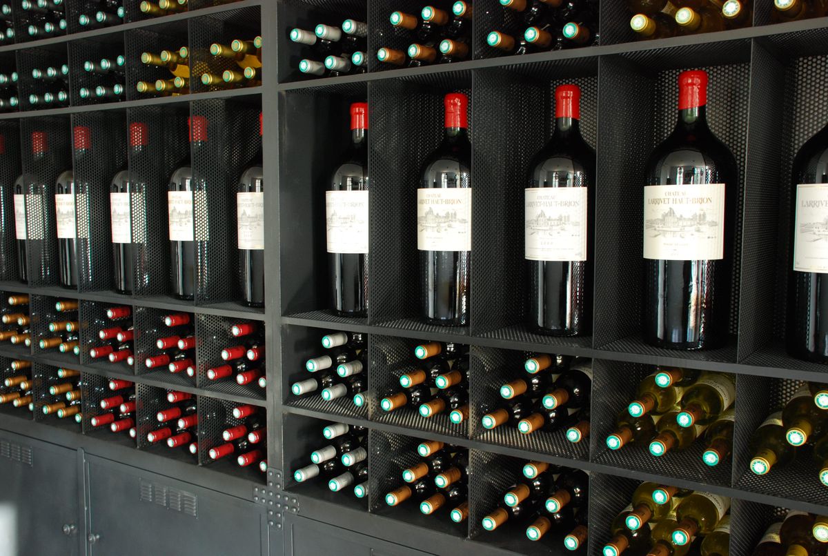 Schwarzes Regal mit liegenden und stehenden Weinflaschen von Chateau Larrivet Haut Brion