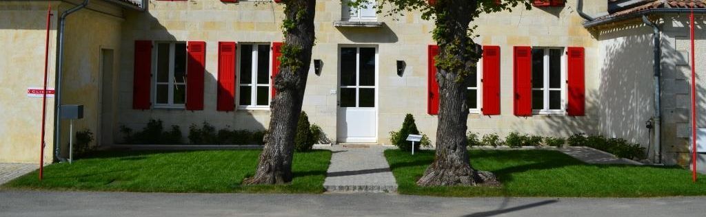 Außenaufnahme Anwesen von Château Clinet mit roten Fensterläden und einer weißen Tür.